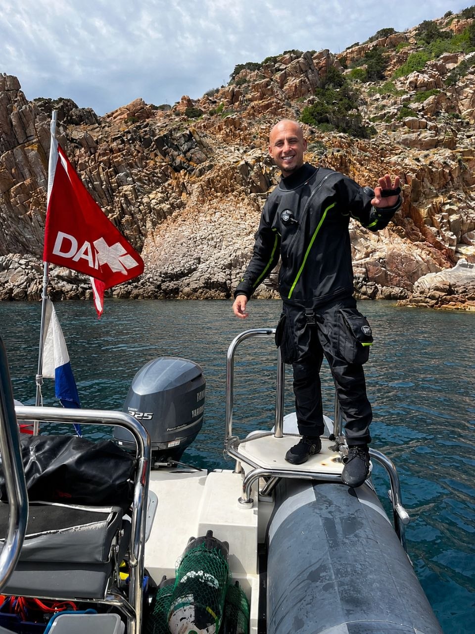 Ahmed im Trockentauchanzug auf dem Schlauchboot vor den Granitfelsen Sardiniens